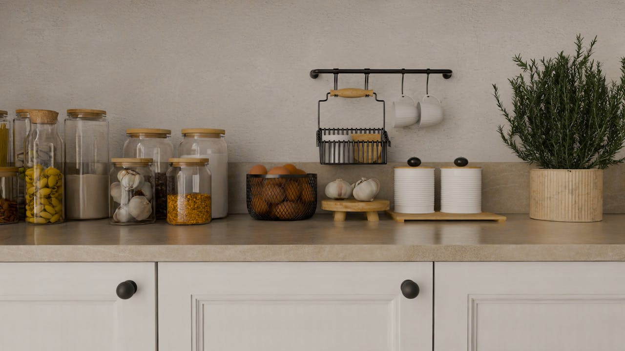 Stylish kitchen setup featuring organic storage jars, herbs, and minimalistic decor on a beige countertop.