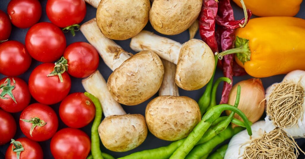 A vibrant assortment of fresh vegetables and mushrooms arranged in a flat lay.